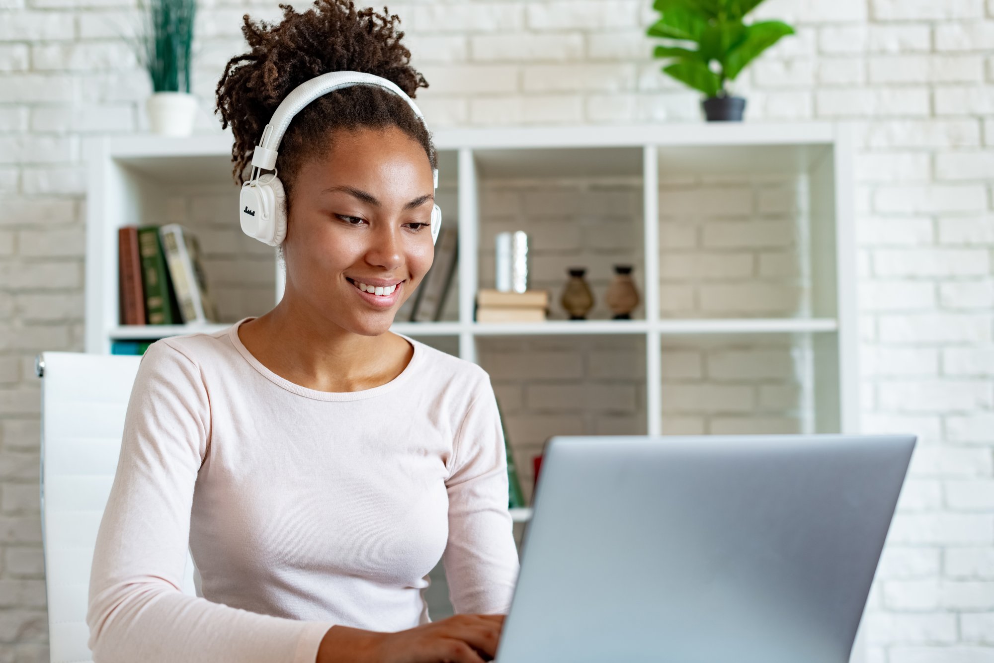 Lady using a laptop and wearing earphones.