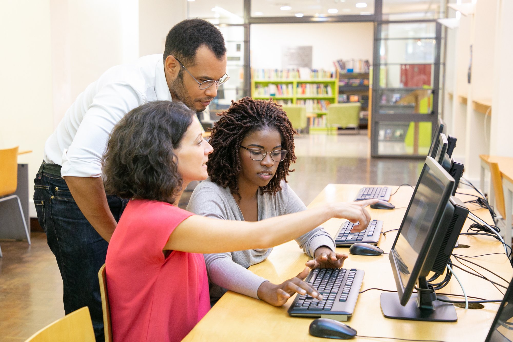 Instructor helping 2 ladies at their computers.